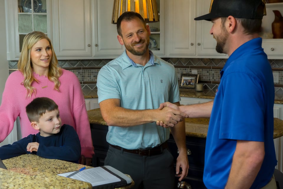A Restoration 1 technician shaking hands with a homeowner inside a kitchen